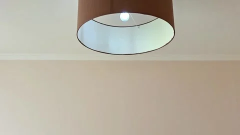 Ceiling Light with Brown Cylindrical Lampshade and Soft Glow Stock Footage 331232574