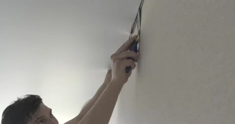 Ceiling master finishes working with canvas, inserts corner into wall mounts Stock Footage 130781448