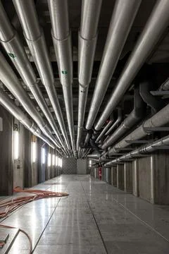 Ceiling mounted industrial pipelines inside underground  building, Long corri Stockfoto's