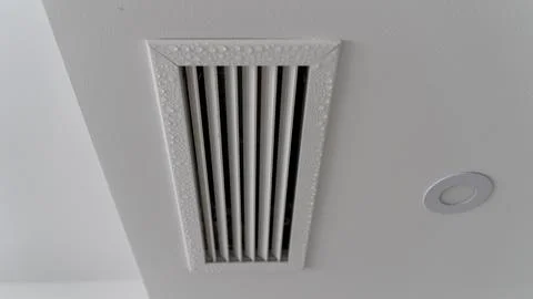 Ceiling Vent With Condensation Drops and Recessed LED Light Close Up 库存照片