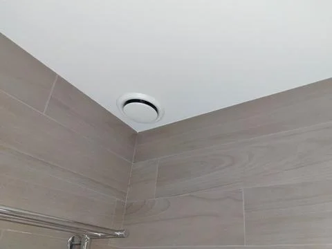 Ceiling vent installed in a modern bathroom with beige tiled walls and a si.. Stock Photos