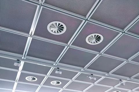 Ceiling of white tiles and ventilation pipes, lights, smoke detectors Stock Photos