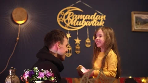 Celebrating Eid al-Fitr, a cute child receives a gift from his parents. Happy Stock Footage 306826356