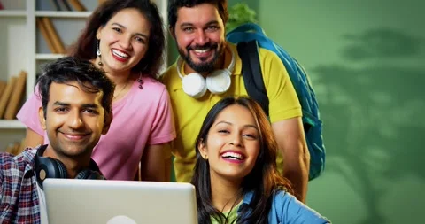 Celebrating success, students point at blank looking at camera using laptop Video stock 342383330