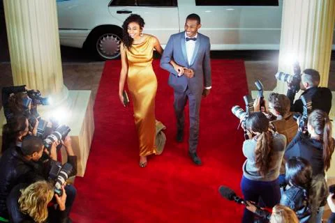 Celebrity couple arriving at red carpet event and being photographed by Stock Photos