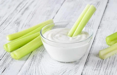 Celery stalk dipped in yogurt Stock Photos