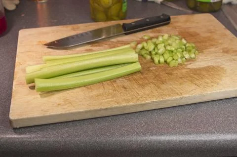 Celery stalks on a cutting board on a kitchen counter with a knife Stock Photos