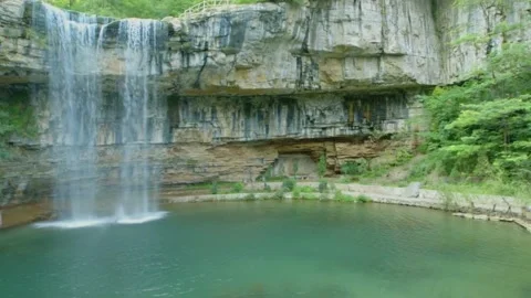 Celestial blue waterfall cascading over a lush cliff. Green water lagoon 스톡 동영상 133353615