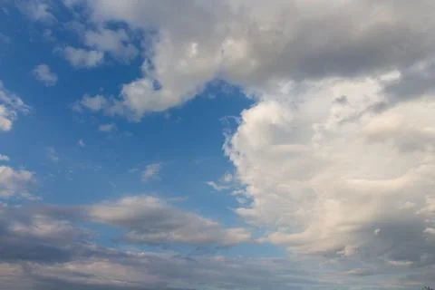 Celestial Dance: The Play of Light and Shadow in the Clouds on a Blue Backg.. Fotos de archivo
