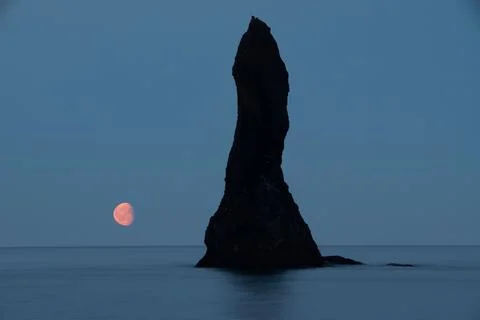 Celestial scene featuring the bright pink moon visible next to the Reynisdrangar Fotos Stock