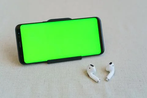 Cell phone and wireless white headphones on table. headphones in focus Stock Photos