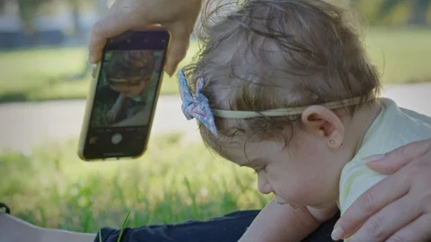 Cell phone being used to take a picture of a baby at park Stock Footage 121187259