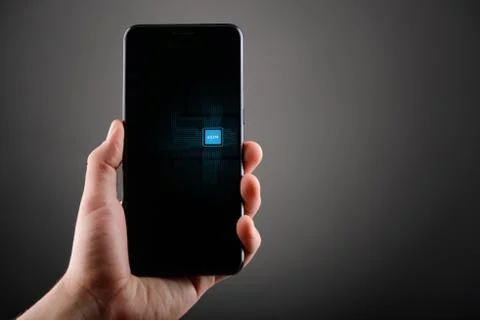 Cell phone with e-SIM card in a male hand on gray background Stock Photos