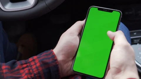 Cell phone with green screen in hands, sitting in car, working in application Stock Footage 116763631