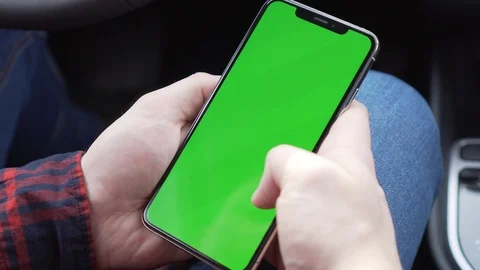 Cell phone with green screen in hands, sitting in car, working in application Stock Footage 116764353