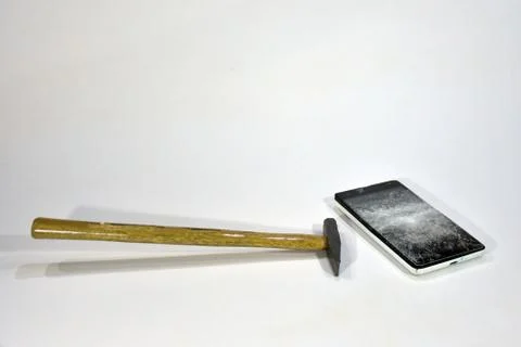 Cell phone with the screen broken by a hammer. Stock Photos