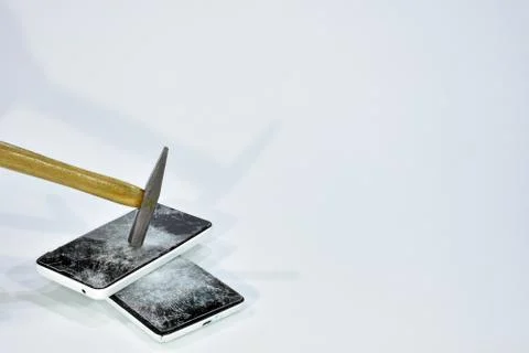 Cell phone with the screen broken by a hammer. Stock Photos
