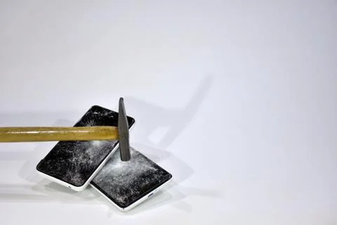 Cell phone with the screen broken by a hammer. Stock Photos