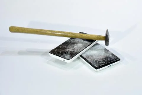 Cell phone with the screen broken by a hammer. Stock Photos