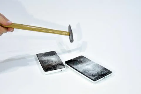 Cell phone with the screen broken by a hammer. Stock Photos