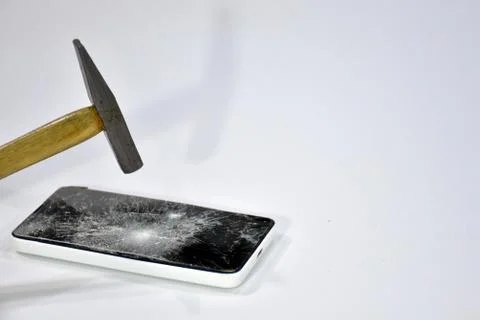 Cell phone with the screen broken by a hammer. Stock Photos
