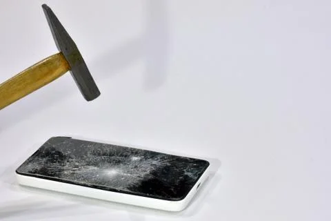 Cell phone with the screen broken by a hammer. Stock Photos