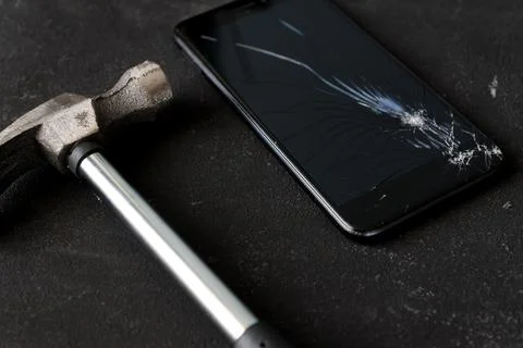 Cell phone with the screen broken by a hammer. close up Stock Photos