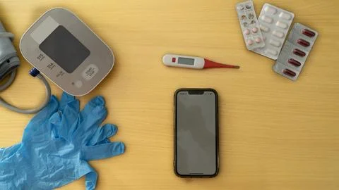 A cell phone is on a table next to a thermometer and a blood pressure cuff Foto stock