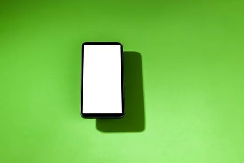Cell phone with white screen on top of a green table. smartphone concept. Whi Stock Photos