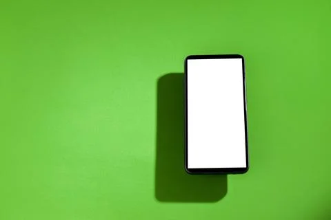 Cell phone with white screen on top of a green table. smartphone concept. Whi Stock Photos
