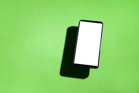 Cell phone with white screen on top of a green table. smartphone concept. Whi Stock Photos