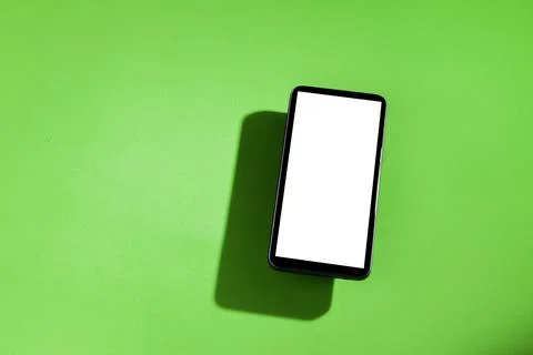 Cell phone with white screen on top of a green table. smartphone concept. Whi Stock-Fotos