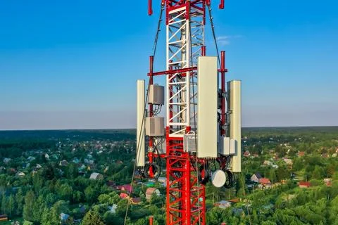 Cell tower against the background of a small village in the forest, Blue sky, Stock Photos