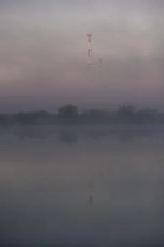 Cell tower and reflections in large ponds in foggy morning Stock Photos