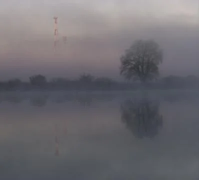 Cell tower and reflections in large ponds in foggy morning Stock Photos