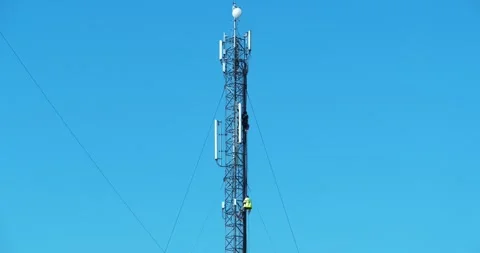 Cell tower on blue background. Maintenance staff at work. High-altitude work Stock Footage 316840020