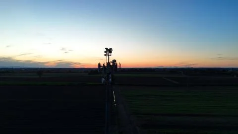 Cell tower rises above ploughed Po Valley fields at twilight, broadcasting .. Stock-Fotos