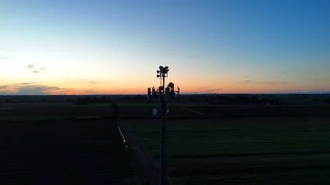 Cell tower rises above ploughed Po Valley fields at twilight, broadcasting .. Stock Photos
