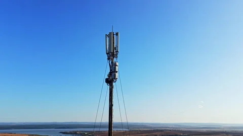 Cell tower standing against a clear blue sky in an open landscape during 스톡 동영상 344777984