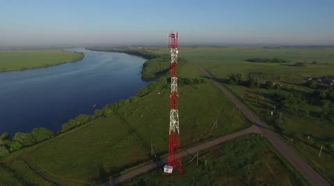 A cell tower stands among the fields by the river. Aerial view. 스톡 동영상 64816612