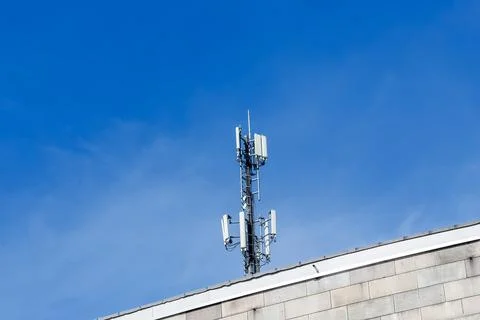 Cell tower transmitting mobile network signal from building rooftop Stock Photos