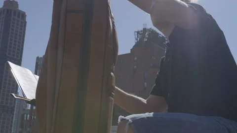 Cellist getting ready to play in sunshine on top of rooftop Stock Footage 111042205