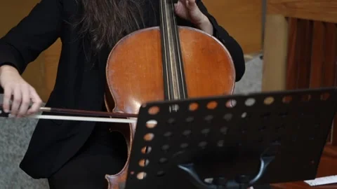 Cellist playing cello with sheet music stand indoors 動画素材 332820028
