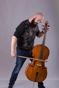 Cellist playing classical music on cello. bearded man fooling around with a m Stock Photos