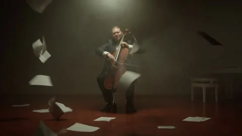 Cellist is playing his cello alone on stage,notes fall from the air Stock Footage 149193973