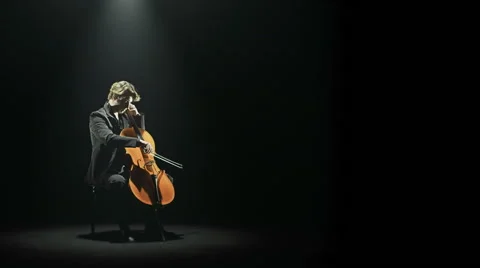 Cellist is tuning his cello alone on stage Stock-Footage 64523676
