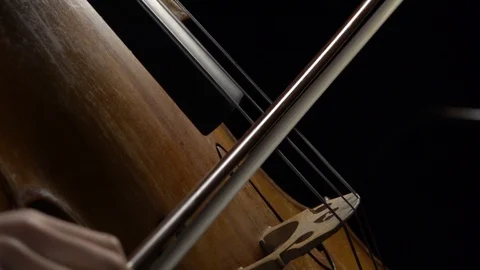 Cello close up of bows carry on the string with notes in a dark room. Side view Stock Footage 99333529