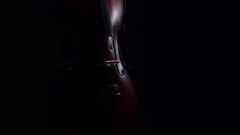 Cello, dimly lit, makes half turn on dark background in studio, front view Stock Footage 167544570