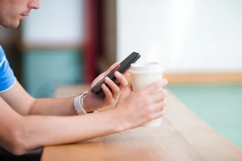 Cellphone and glass of coffee in cafe closeup. Man using mobile smartphone. Boy Stock Photos