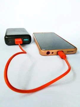Cellphone being charged using a power bank with isolated white background Stock Photos